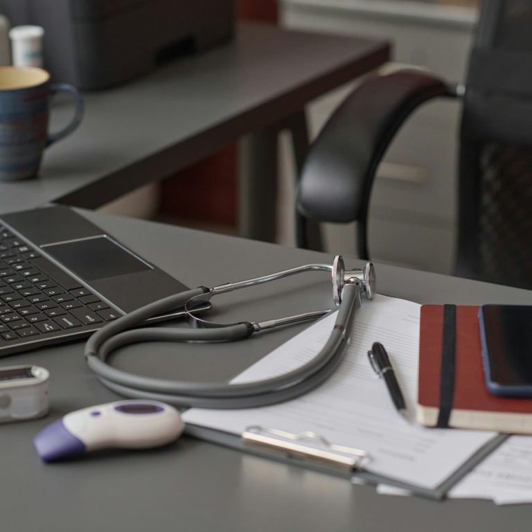 Echipament medical pe un birou cu laptop deschis.